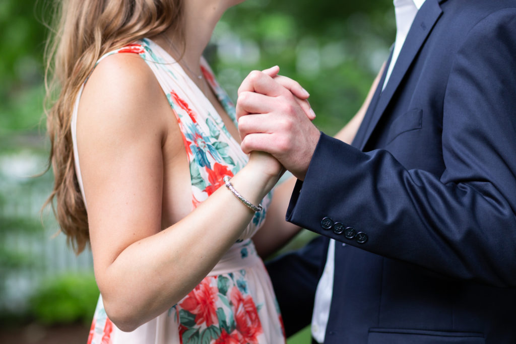 Close-up photo of an engaged couple's hands while dancing.