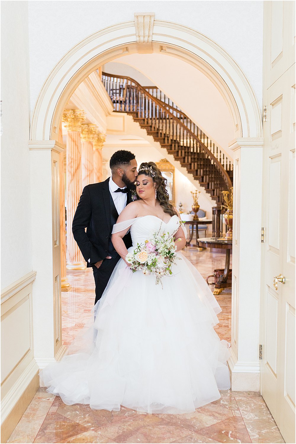 Bride and groom pose for photo together under a arched doorway at The Estate at River Run during whimsical spring wedding editorial