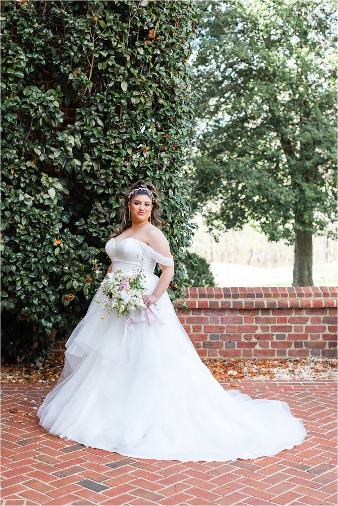 bride poses in front of lush greenery at the estate at river run during whimsical spring wedding editorial