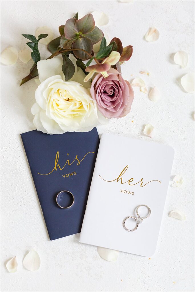 flat lay detail shot - roses, hellebores, flower petals and vow booklets