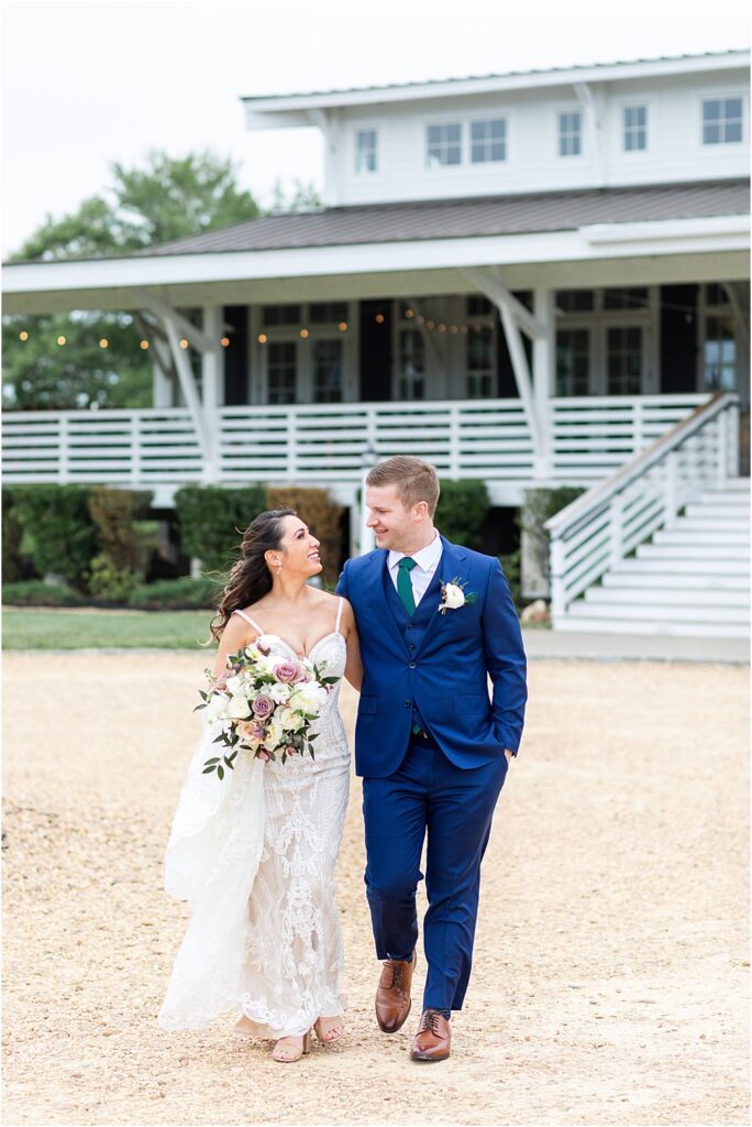 The couple walks together in front of upper Shirley vineyards, gazing lovingly at one another during their modern romantic wedding in Charles City, VA