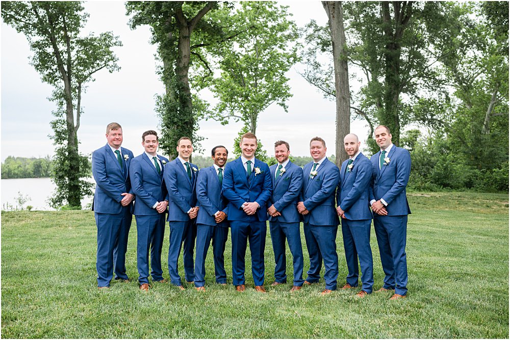 John and his groomsmen stand on the green lawn in front of the James River at Upper Shirley in Charles City, VA.