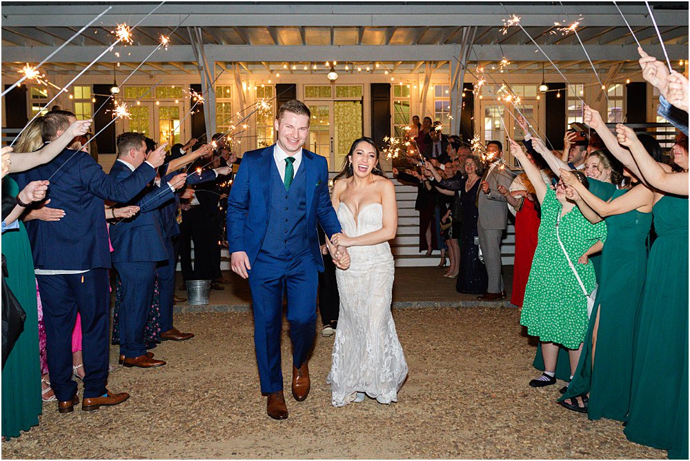 John and Stephanie walk through their guests, holding sparklers, during their grand exit at the end of their modern romantic wedding in Charles City, VA