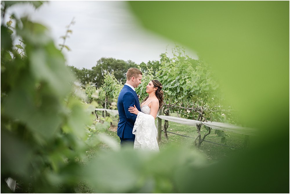 Bride and groom embrace in the vineyard during their romantic wedding ceremony in Charles City, VA