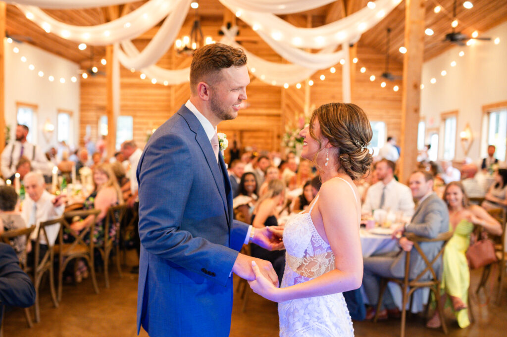 the bride and groom share their first dance during romantic barn wedding reception