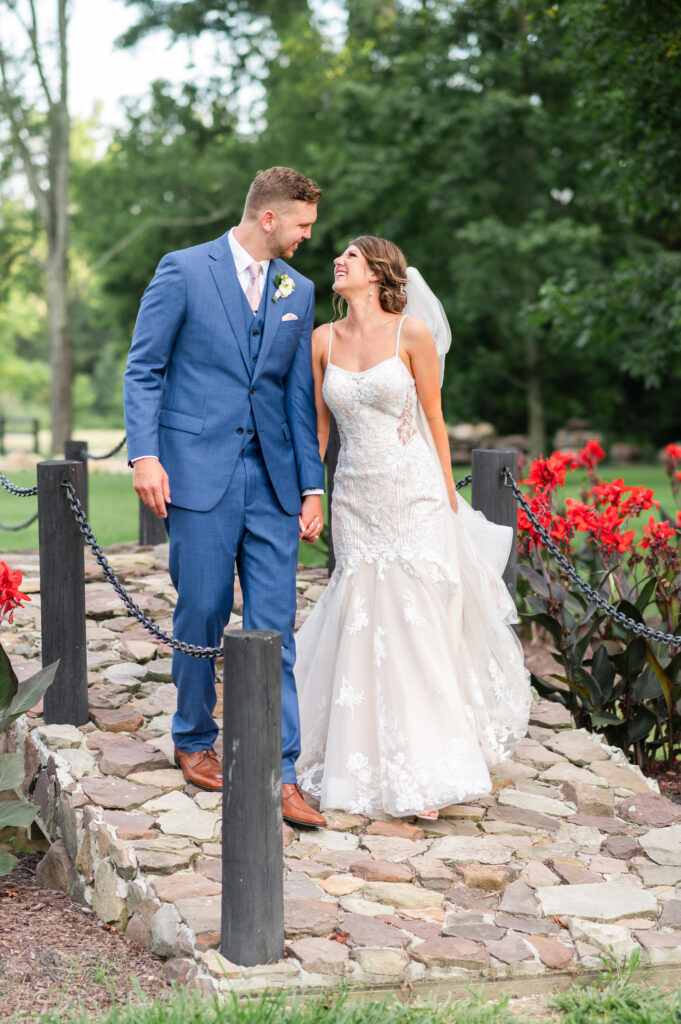 bride and groom stroll along stone footbridge on the grounds at Altria Farm during during romantic barn wedding day