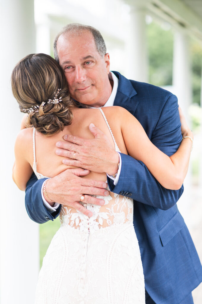 father of the bride hugs the bride during father-daughter first look on romantic barn wedding day in King William, VA