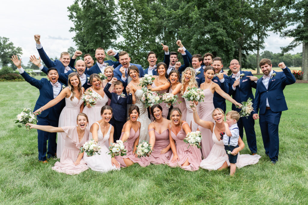 The entire wedding party gathers together for a silly photo during romantic barn wedding in King William, VA