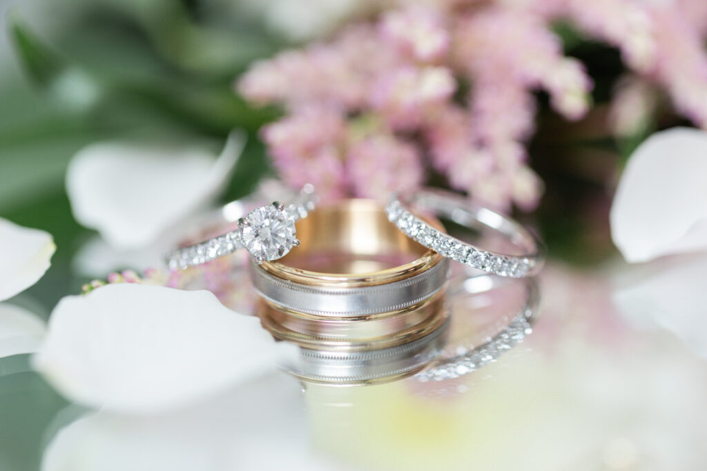 wedding bands and engagement ring set against floral backdrop
