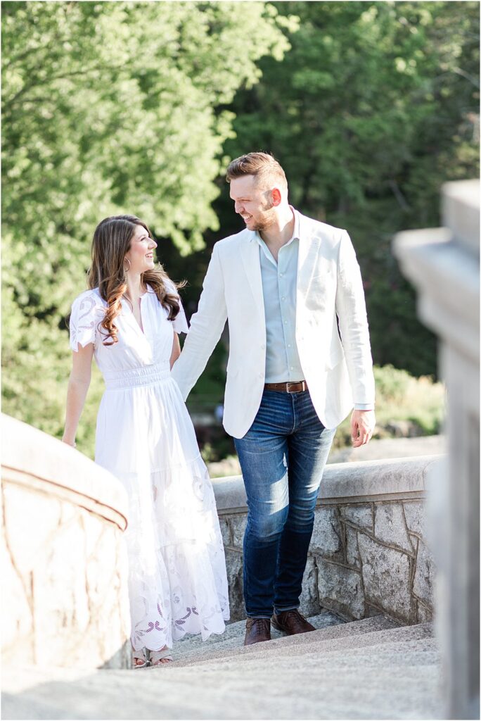 Dan gently places his hand at the small of Olivia's Back to gently guide her up a stone staircase at Maymont Park during their effortlessly chic engagement session in RVA. The couple smiles at each other