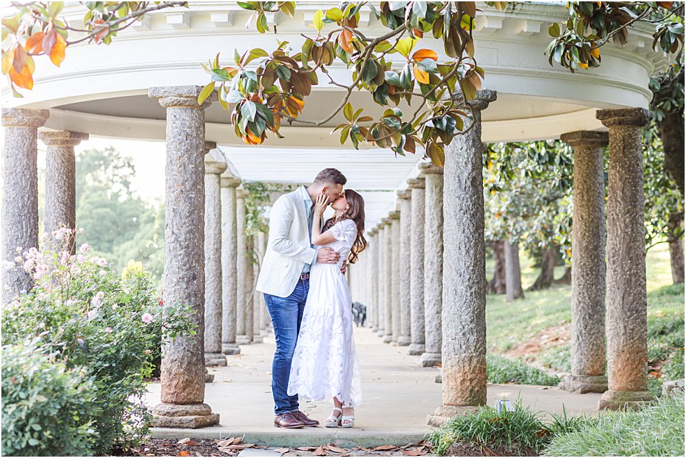 Olivia and Dan kiss beneath he columns of the Italian Garden at Maymont Park during their effortlessly chic engagement session.