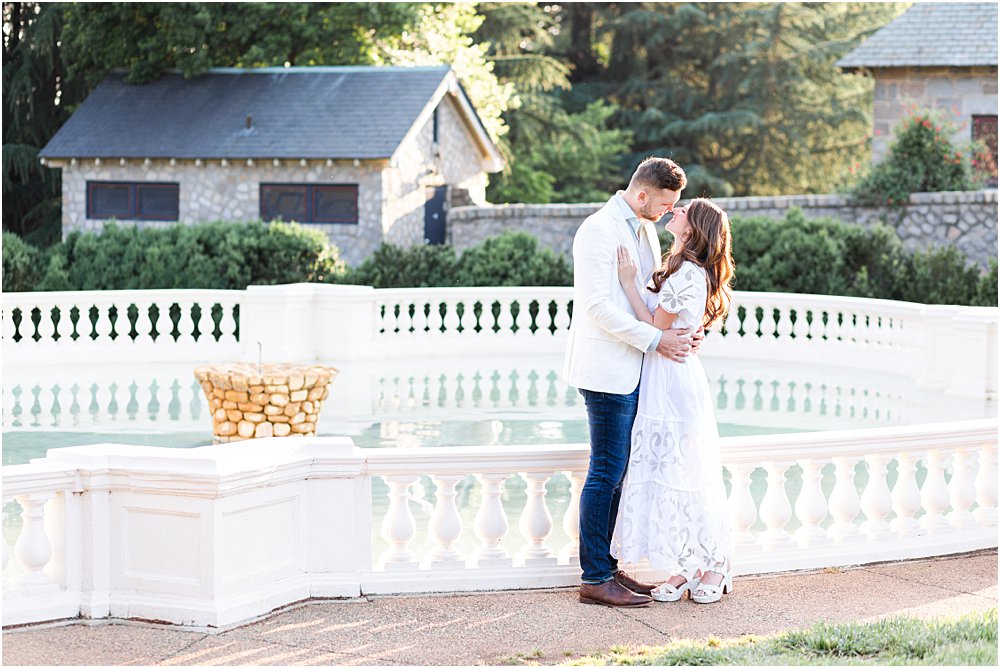 The couple tenderly touch the tips of their noses together in front of a fountain at Maymont Park during their effortlessly chic engagement session