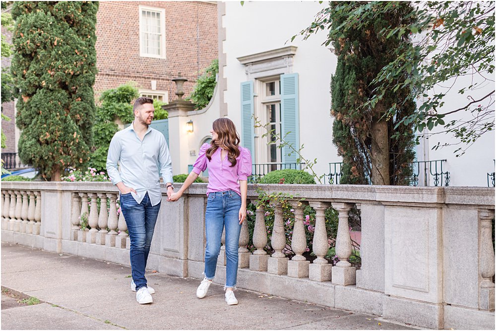 Dan and Olivia, clad in jeans and brightly colored button downs, stroll hand in hand gazing happily at one another during their effortlessly chic engagement session in Richmond, VA
