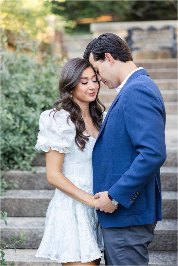 Raphael snuggles his head into Gabriella's hair. Her eyes are closed. He gently takes her hand during classic engagement session at Maymont Park in Richmond, VA.
