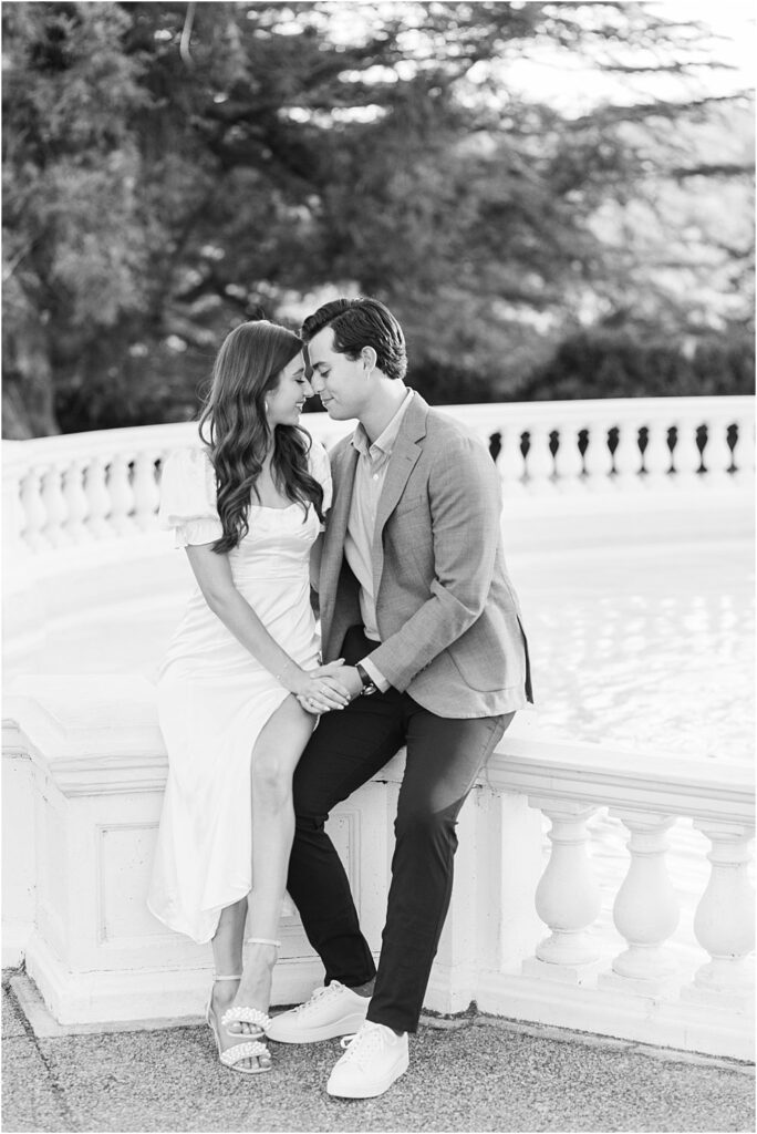 Gabriella and Raphael sit on the balustrade railing, forehead to forehead, during classic engagement session at Maymont Park in Richmond, VA.