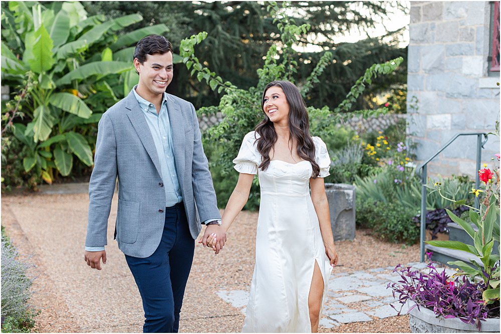 Gabriella dn Dan smile and laugh while walking together during classic engagement session at Maymont Park in Richmond, VA.