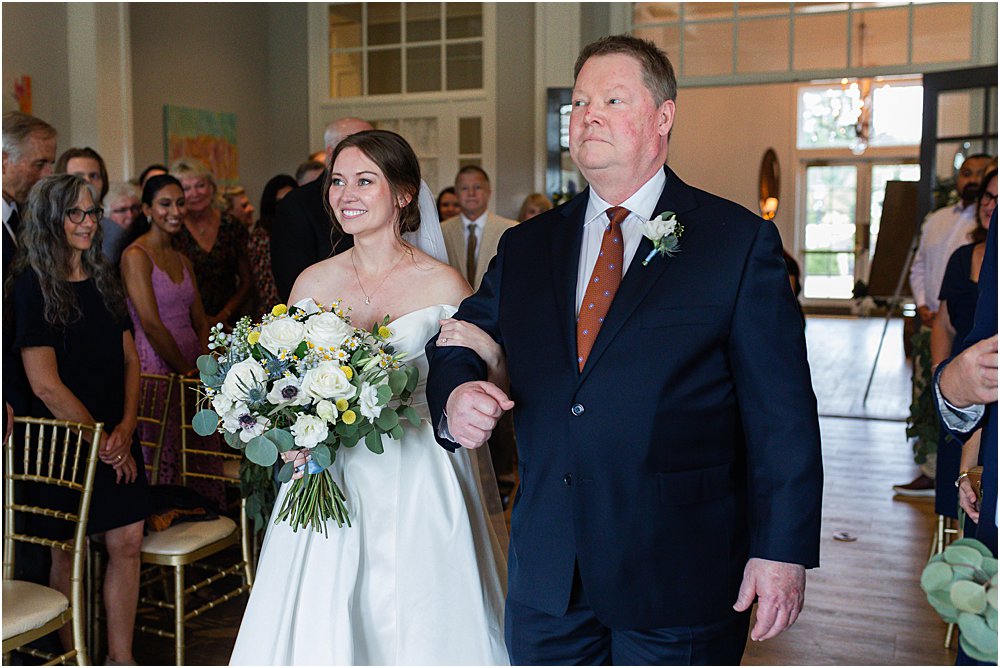 Father walking daughter down the aisle arm in arm at Estate at Independence during a wedding ceremony