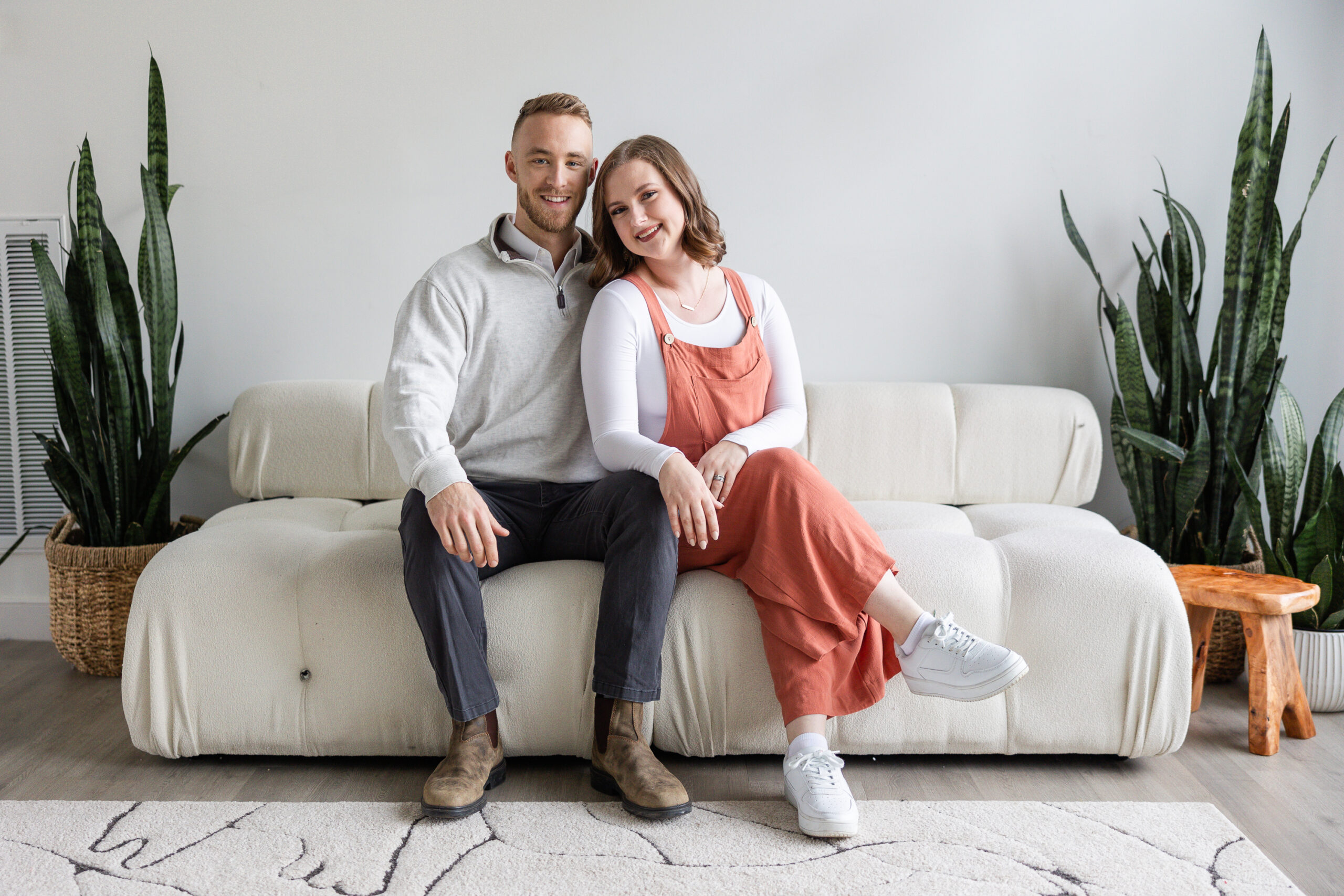 Couple seated on a couch with their arms around one another in a branded headshot session.