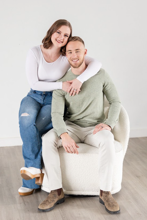 Couple standing sitting a chair with their arms around each other during a branded headshot session.